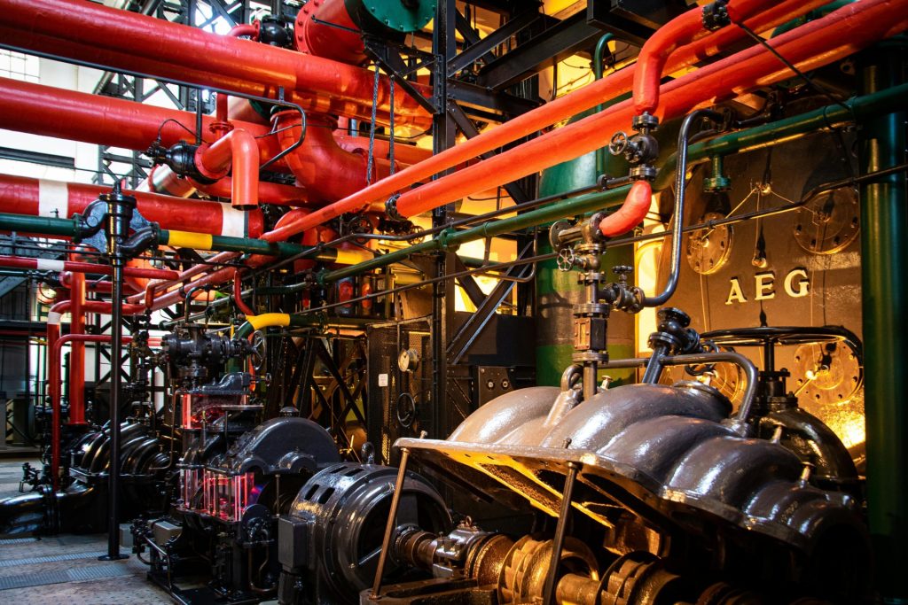 Lebendige Industriemaschinen mit roten Rohren und komplexen Anlagen in einer Fabrik.